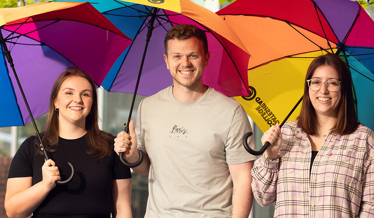 Gateshead Colleges School Liason Team smiling to camera, holding rainbow coloured umberellas